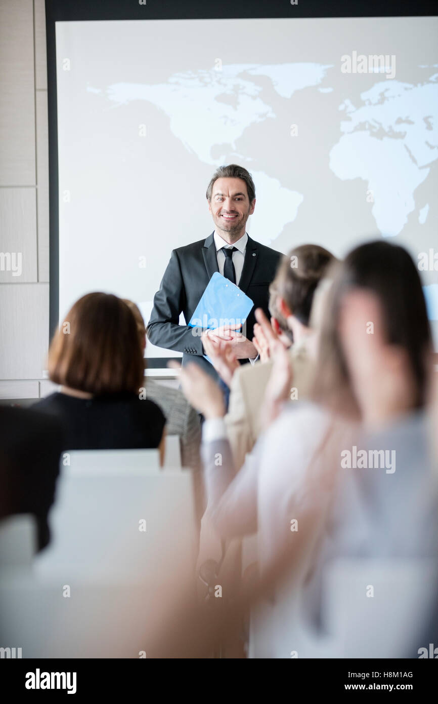 Happy public speaker looking at audience applauding during seminar Stock Photo