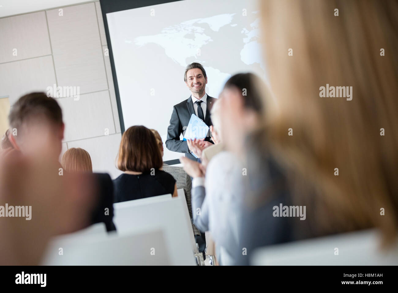 Confident public speaker looking at audience applauding during seminar Stock Photo