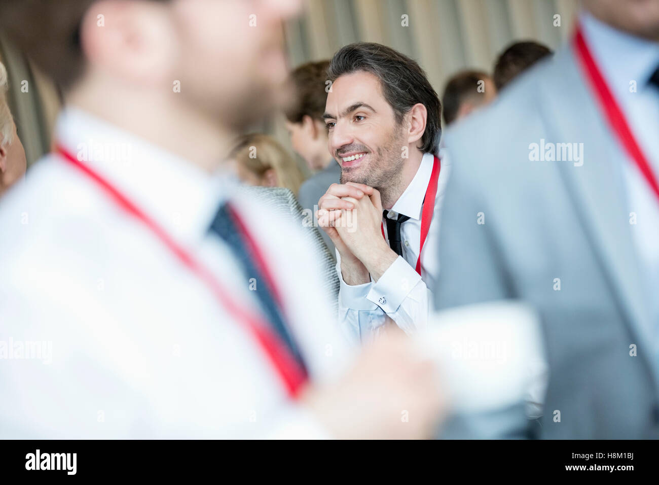 Thoughtful businessman with hands clasped at lobby in convention center Stock Photo