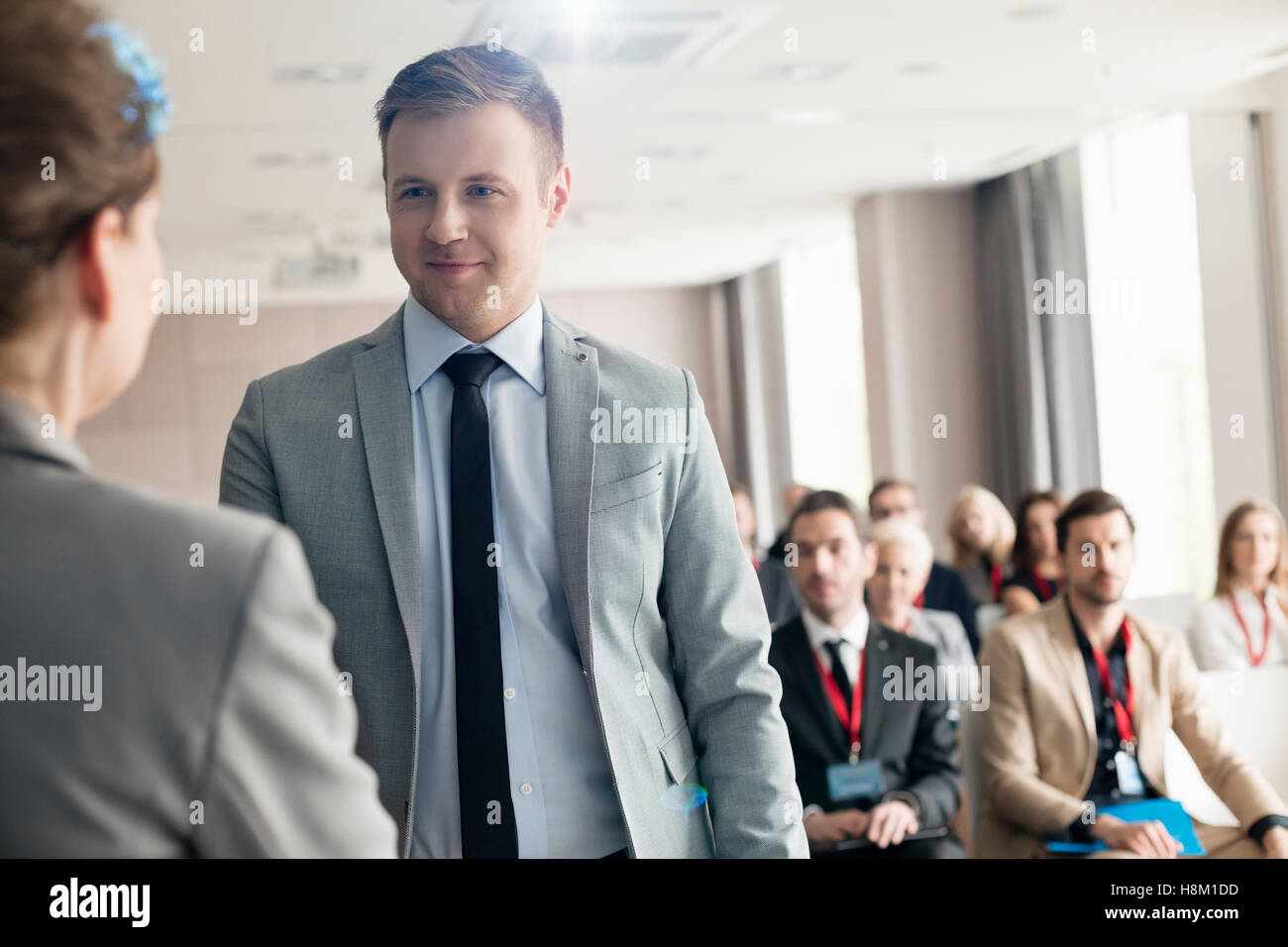 Confident businessman looking at public speaker during seminar Stock Photo