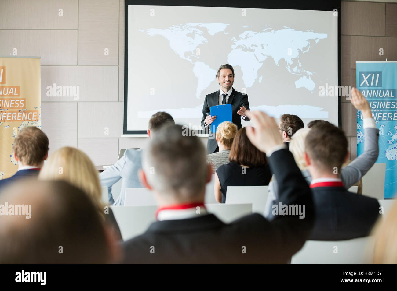 Smiling public speaker asking questions to audience during seminar Stock Photo