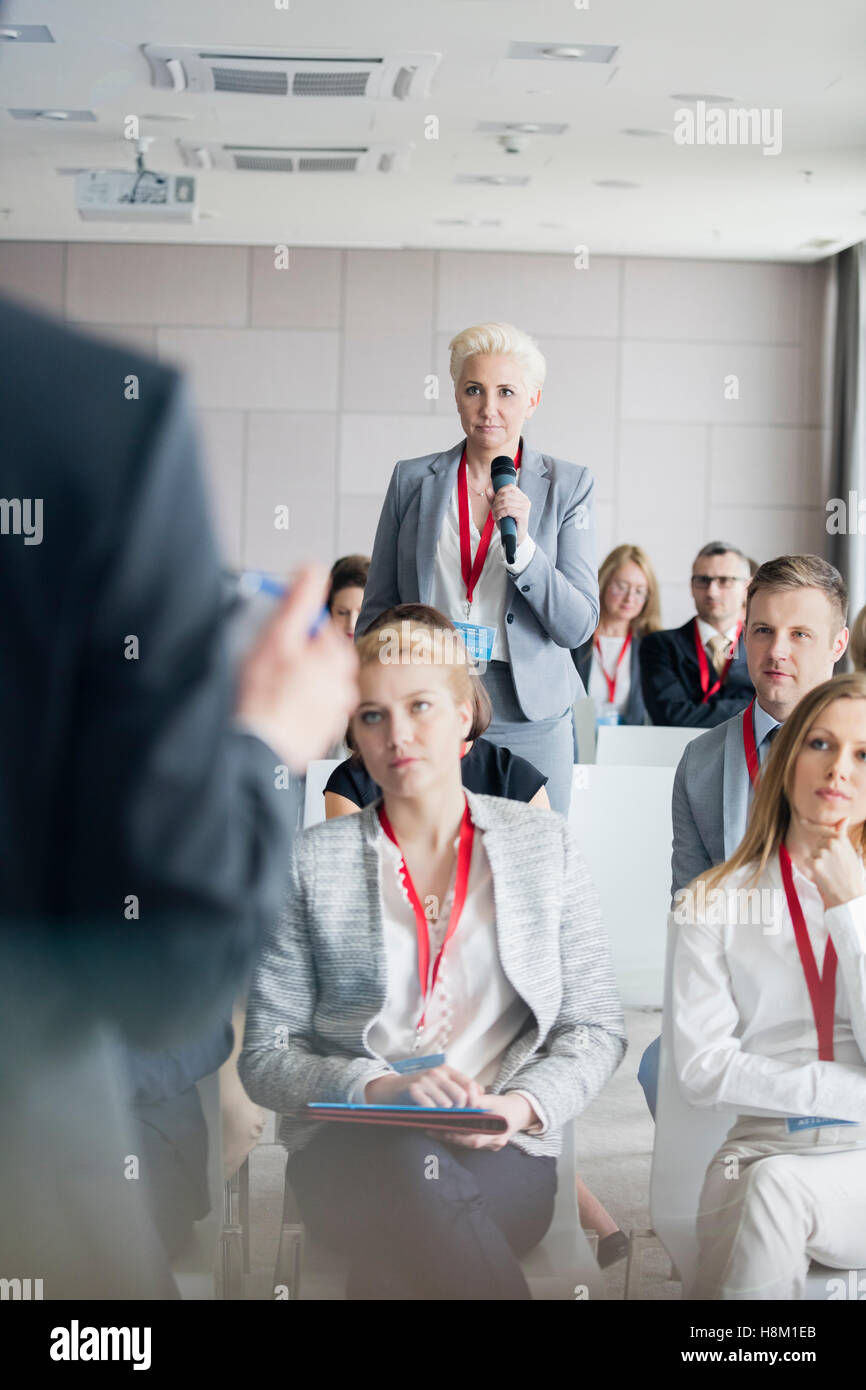 Businesswoman asking questions to public speaker during seminar Stock Photo