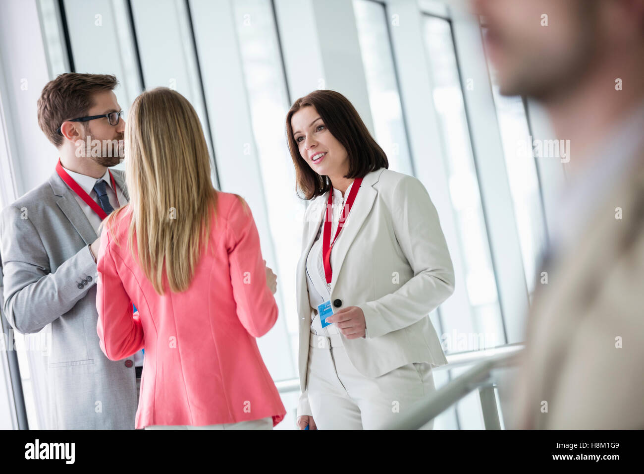 Confident business people discussing in brightly lit convention center Stock Photo