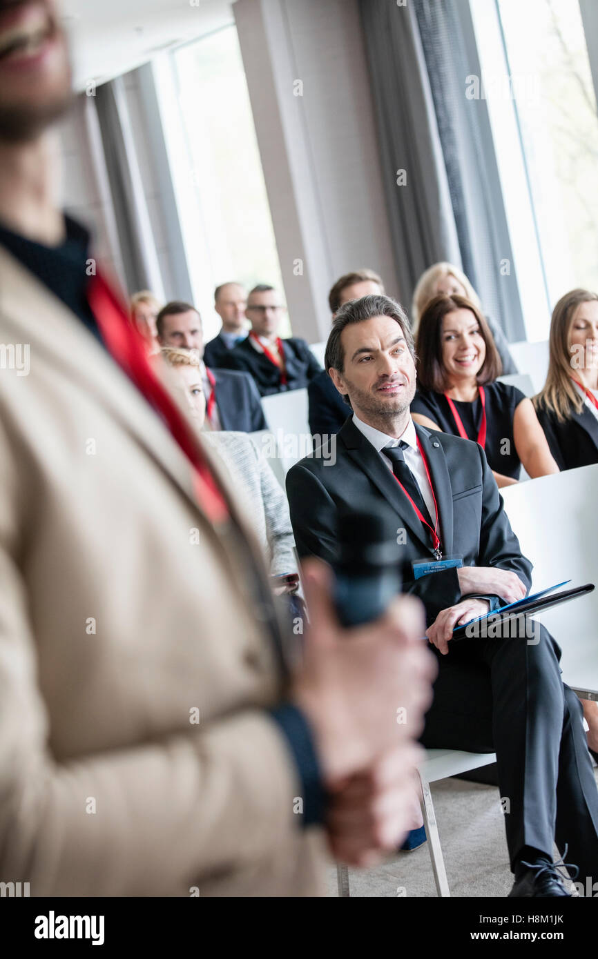 Midsection of public speaker with business people in seminar hall Stock Photo