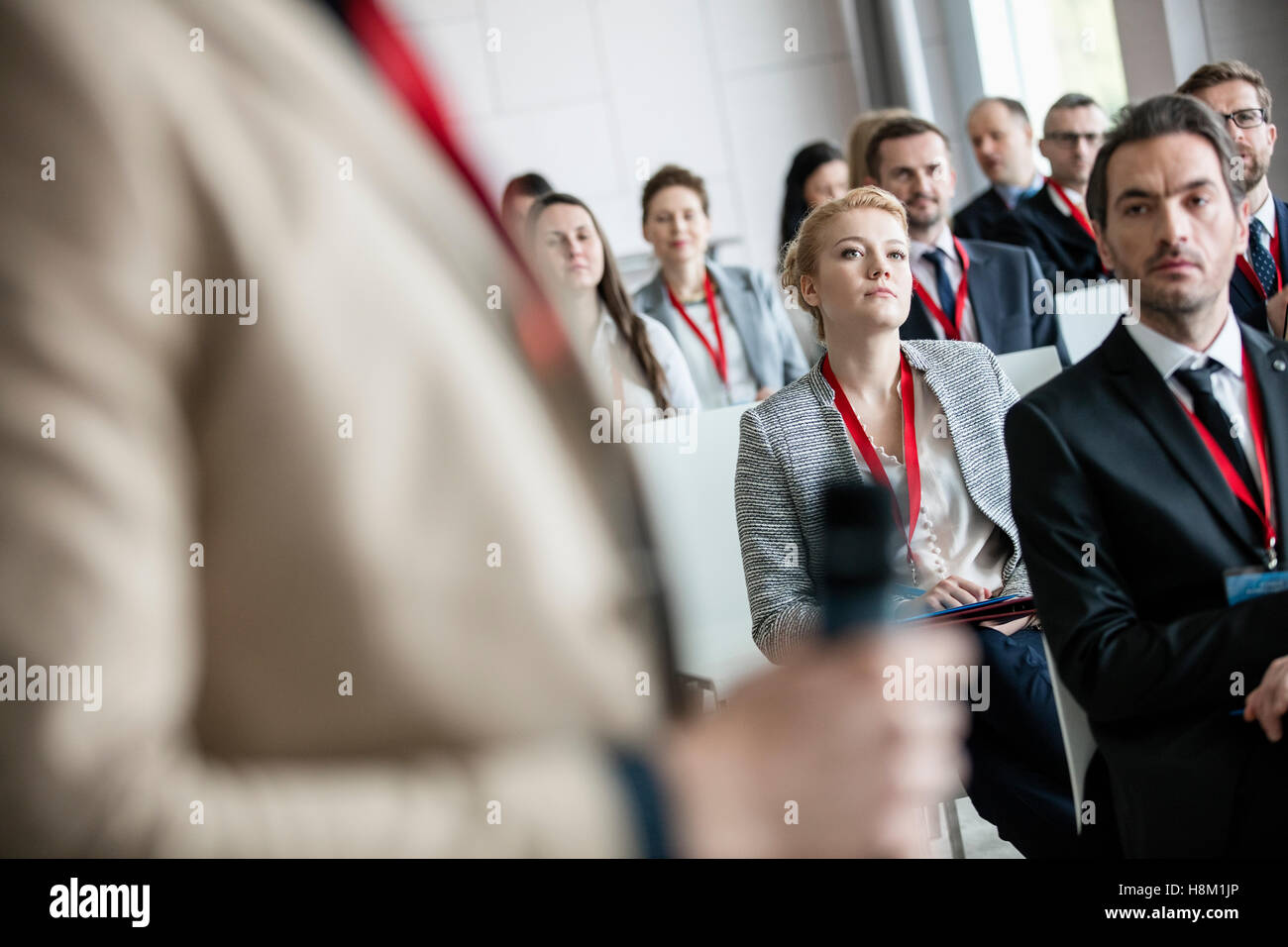 Businessman looking at public speaker in convention center Stock Photo