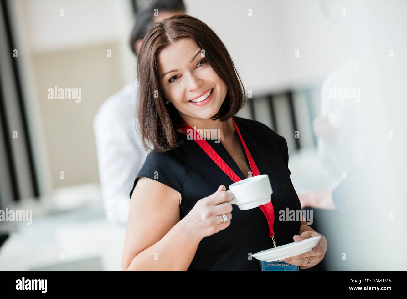 Portrait of happy businesswoman holding coffee cup in seminar hall Stock Photo