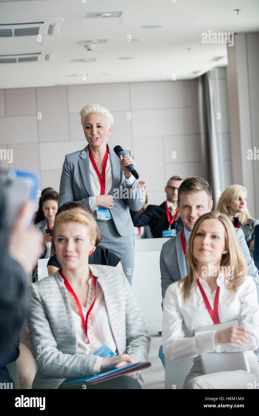 Businesswoman asking questions during seminar Stock Photo