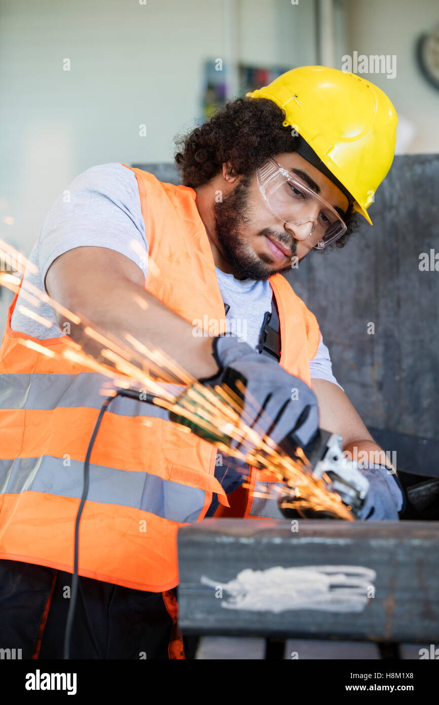 Young manual worker in protective workwear grinding metal in industry Stock Photo