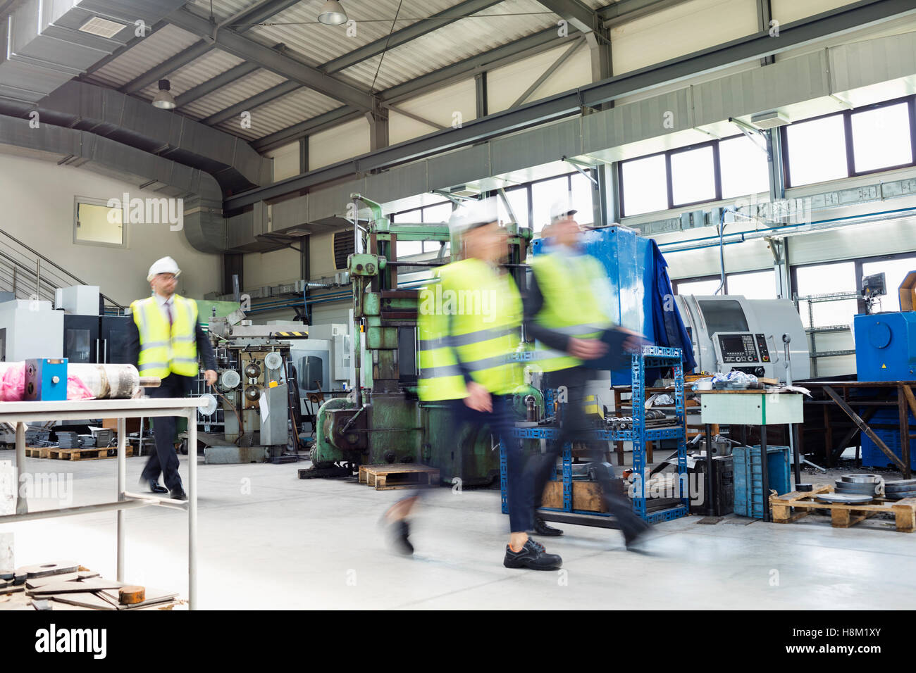 Blurred motion of business people wearing reflective clothing walking in metal industry Stock Photo