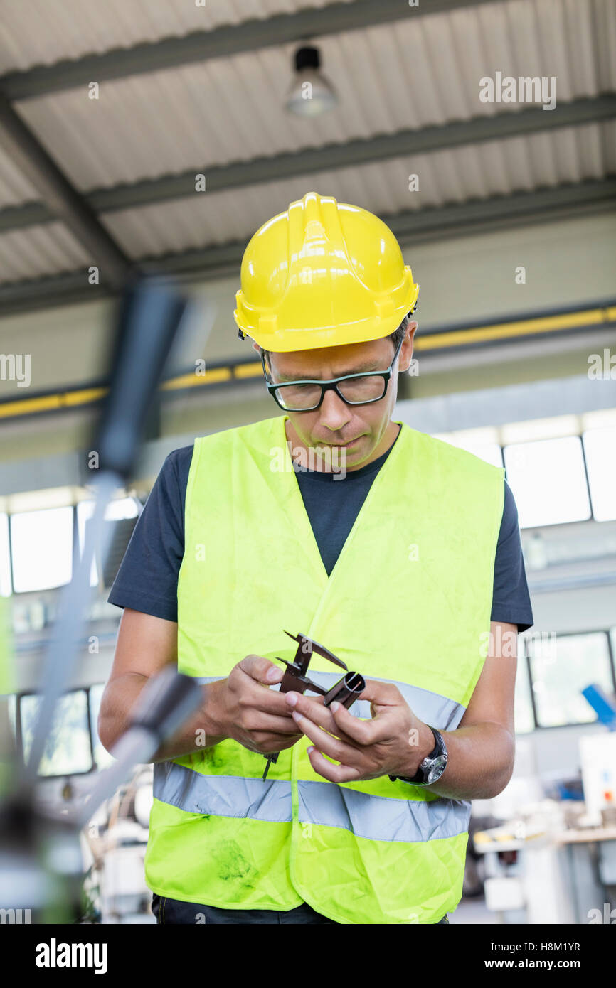 Mid adult manual worker measuring metal with caliper in industry Stock Photo