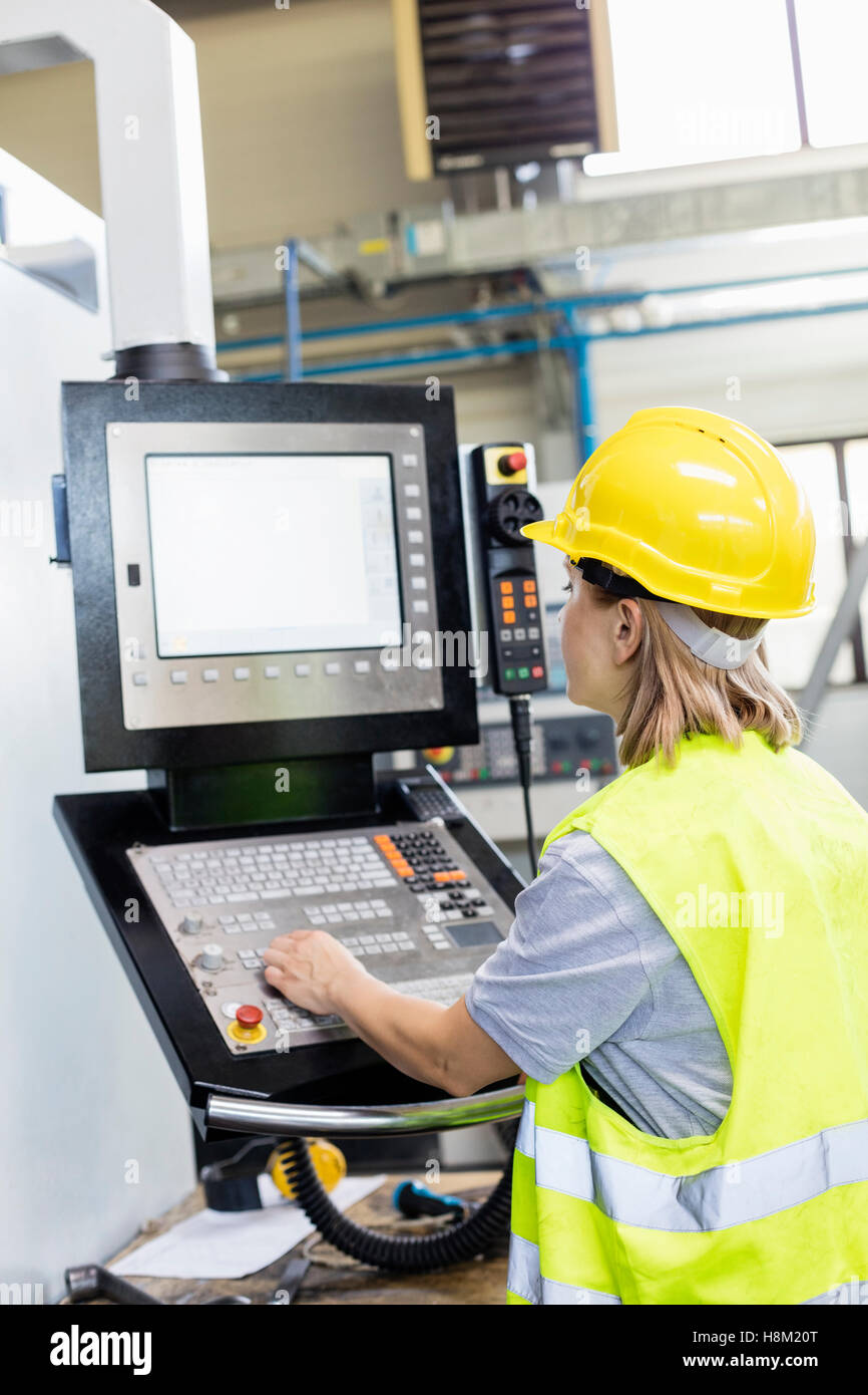 Female worker operating machinery at control panel in factory Stock Photo