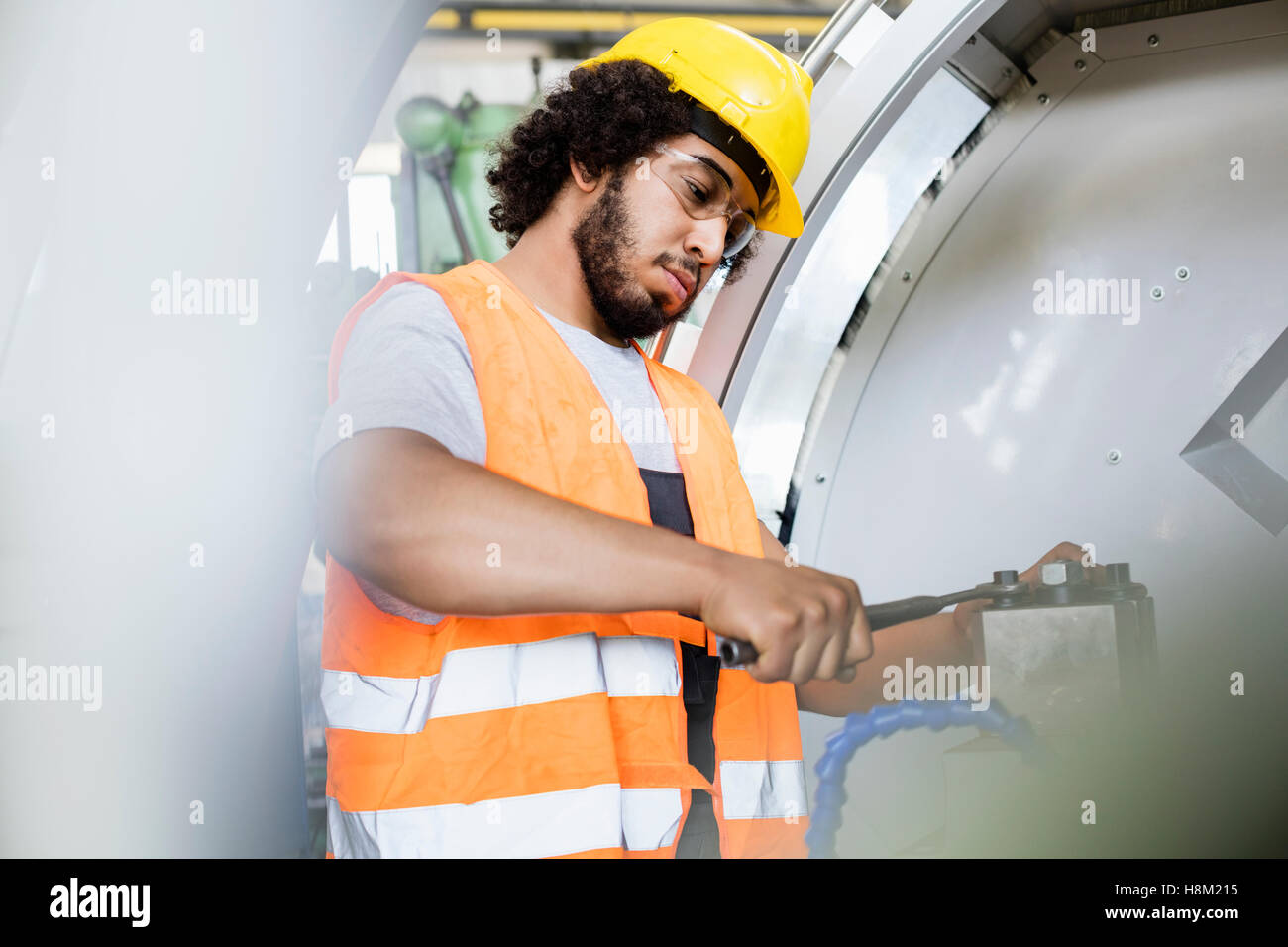 Young manual worker tightening bolts on machinery in factory Stock Photo