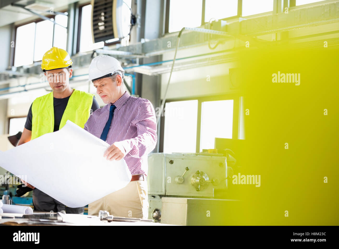 Male architect and manual worker examining blueprint in metal industry Stock Photo