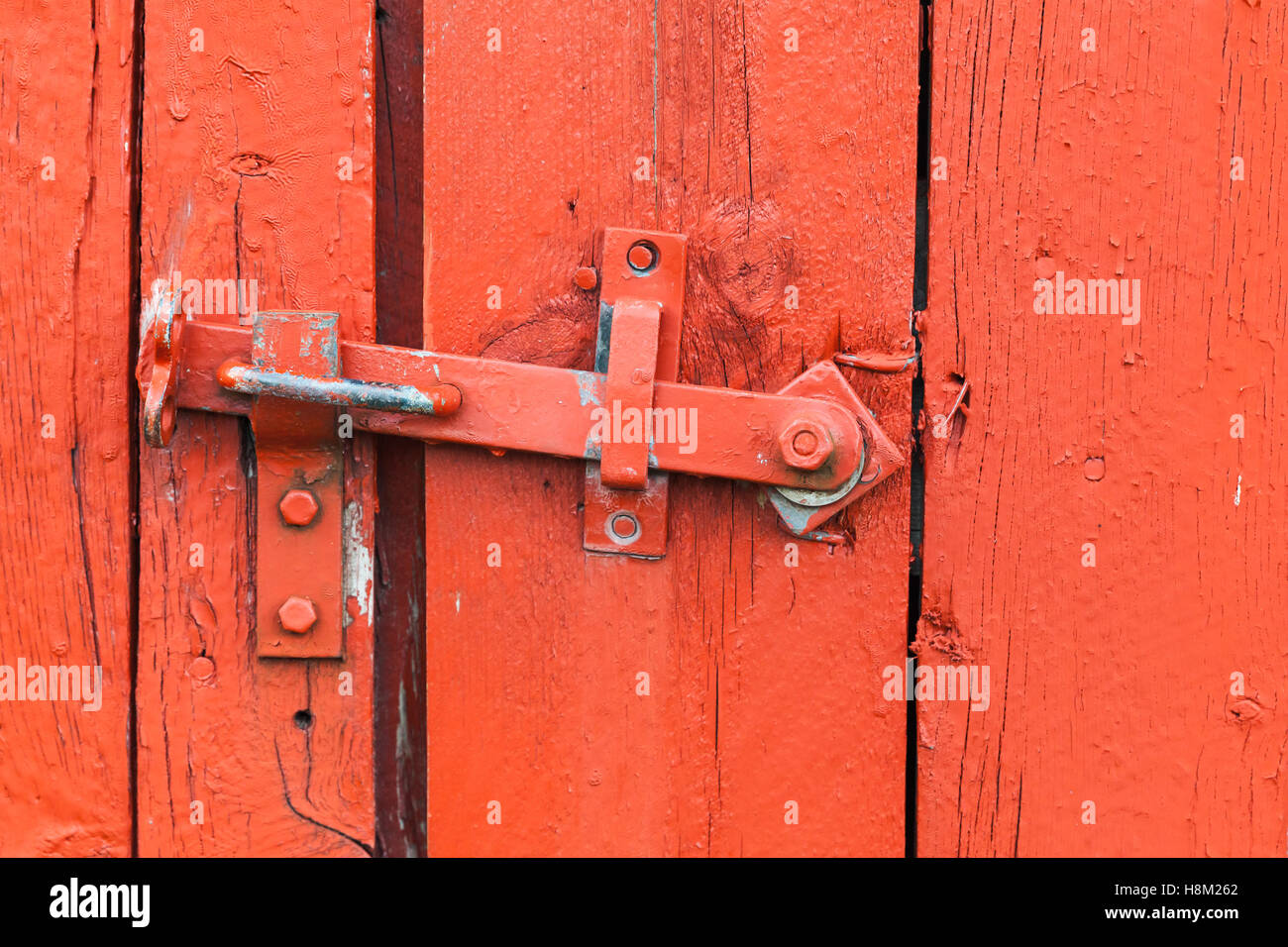 Old metal latch on red wooden door, close-up photo Stock Photo