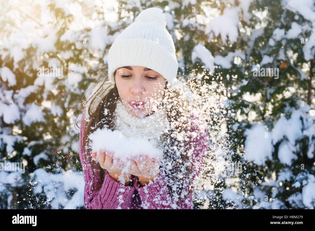 beautiful young woman holding a snow and blowing on it Stock Photo