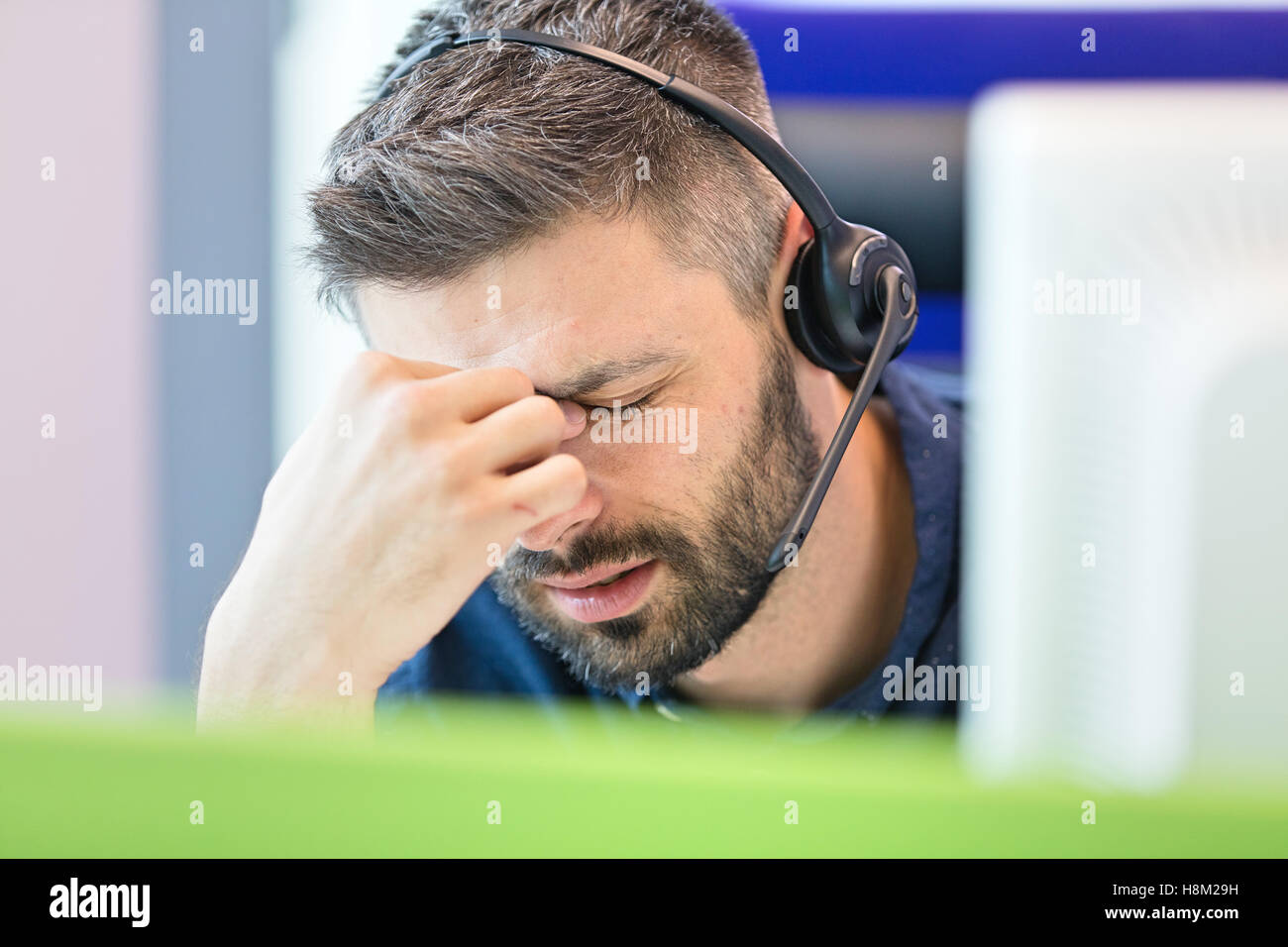 Tired mid adult businessman wearing headset while pinching bridge of