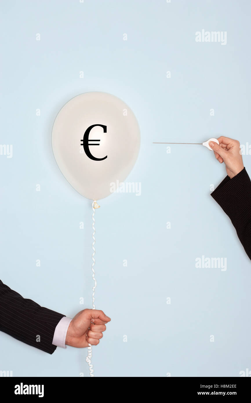Cropped hands holding needle and popping balloon with EURO symbol Stock Photo