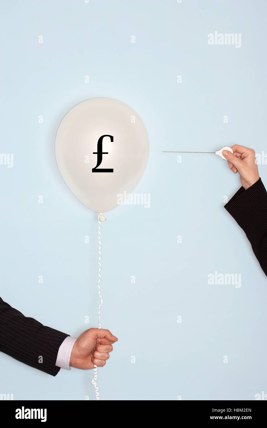 Cropped hands holding needle and popping balloon with pound symbol Stock Photo