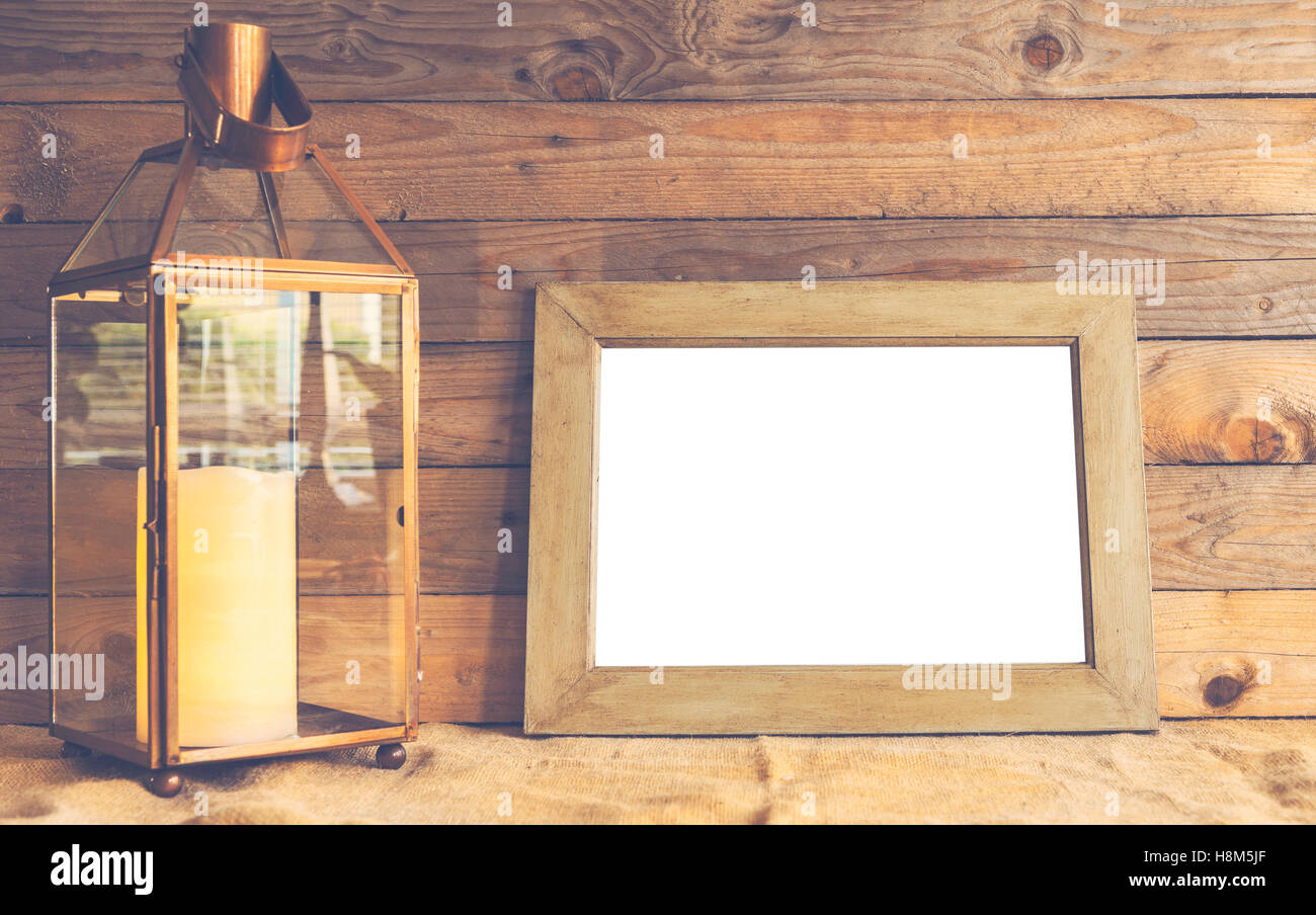 Image of rustic scene with copper lantern, empty frame and wooden background. Stock Photo