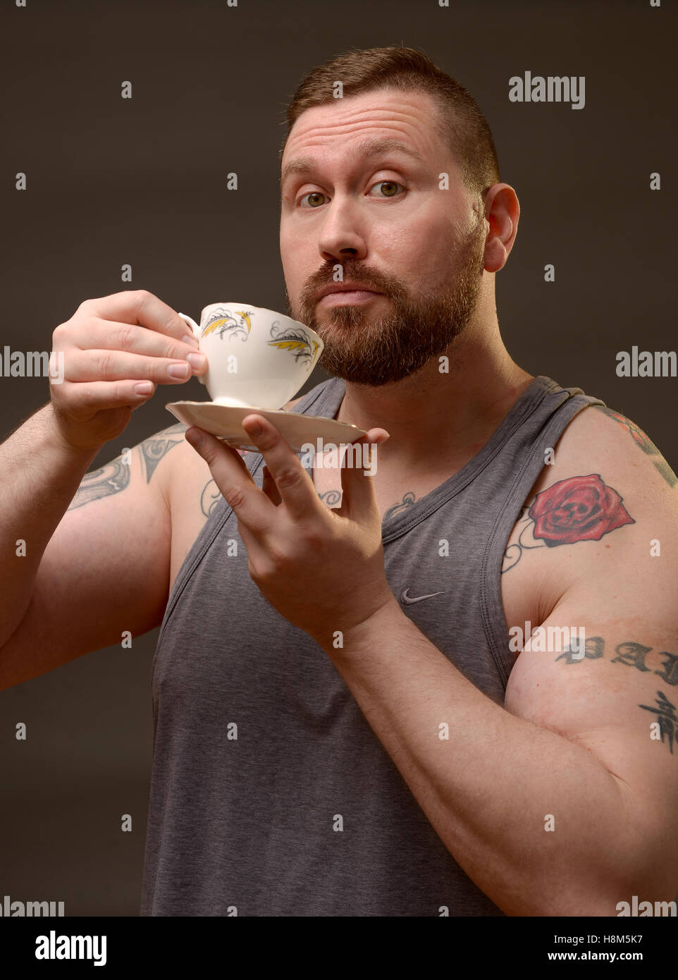 A tough strong man drinking a delicate cup of tea. Stock Photo