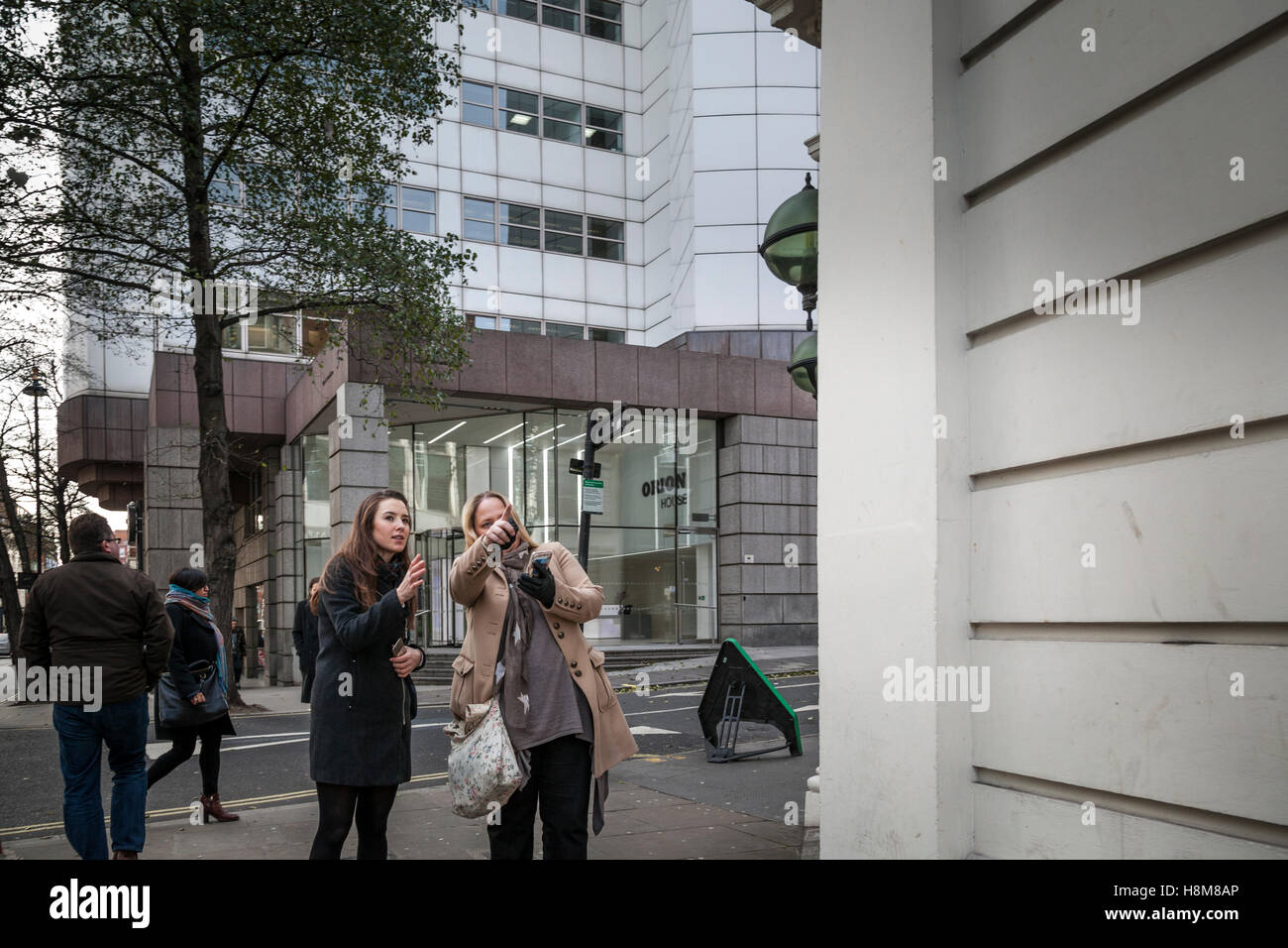 A woman tourist is given directions by another on the streets of London. Stock Photo