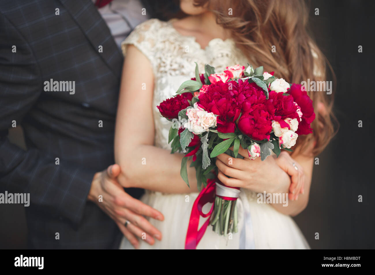 Wedding couple hugging, the bride holding a bouquet of flowers in her ...