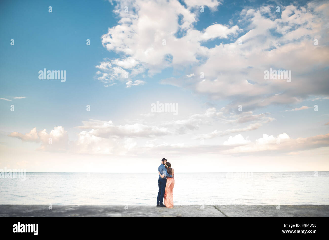 Beautiful loving couple, pride with long dress walking on pier Stock Photo
