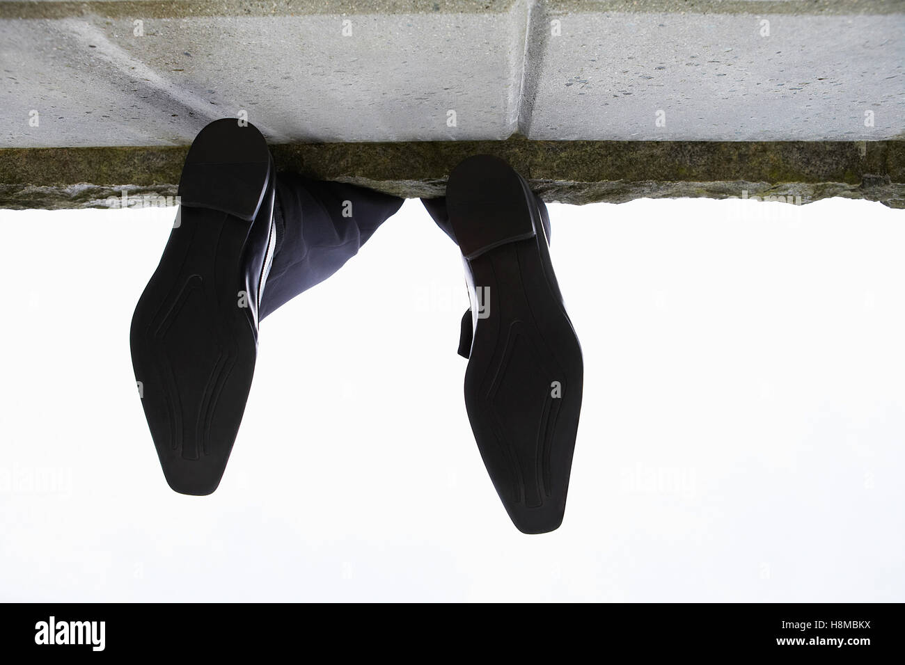 Feet dangling over wall, low angle view Stock Photo