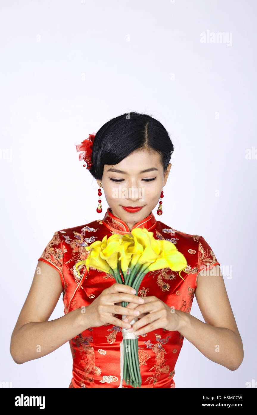 pretty chinese young woman holding a bunch of yellow daffodils Stock Photo