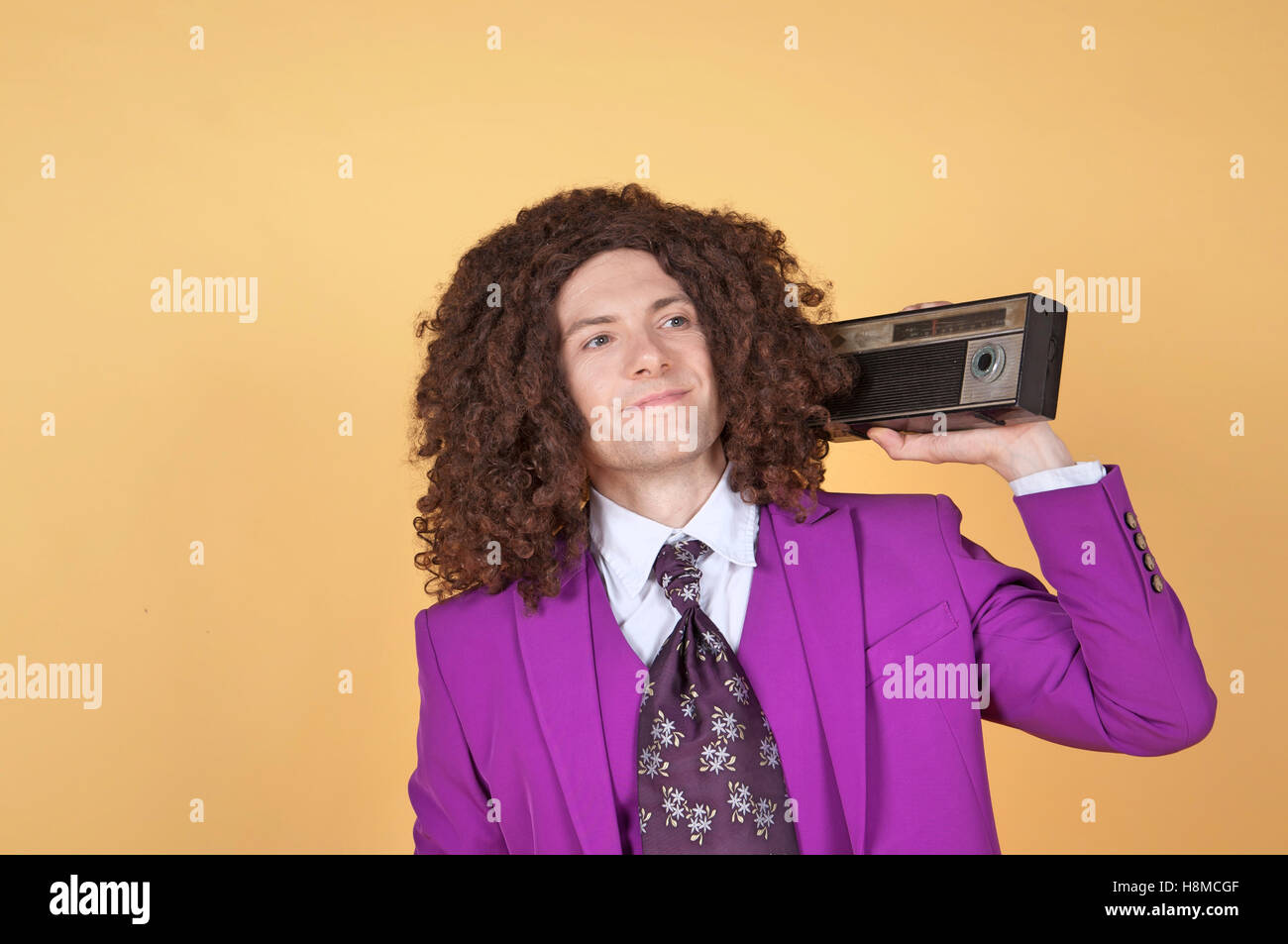 Caucasian man with afro wearing Purple Suit listening to music Stock Photo