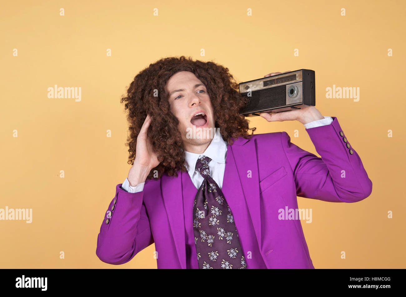 Caucasian man with afro wearing Purple Suit listening to music Stock Photo