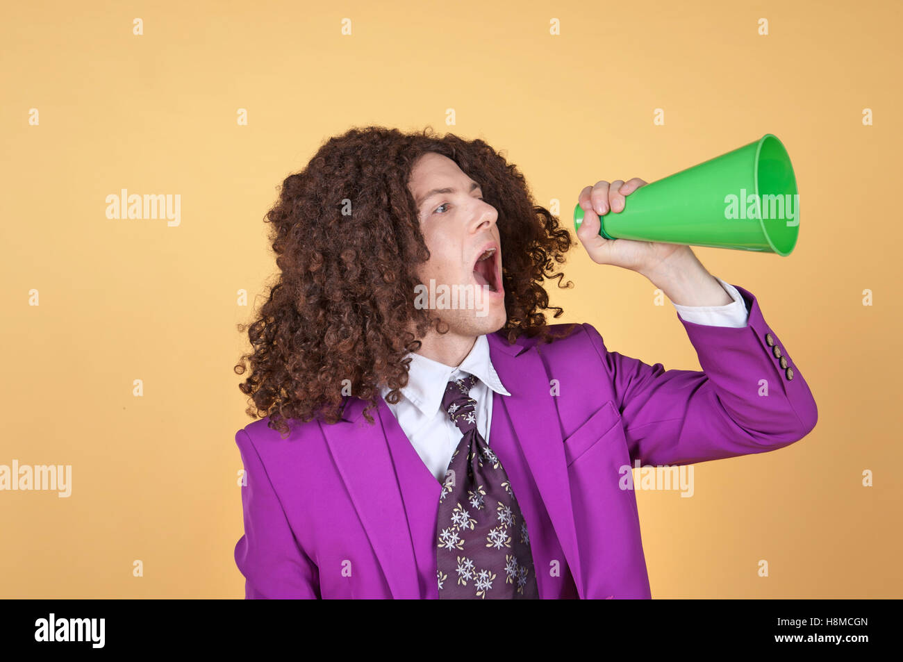 Caucasian man with afro wearing Purple Suit shouting from a cone Stock Photo