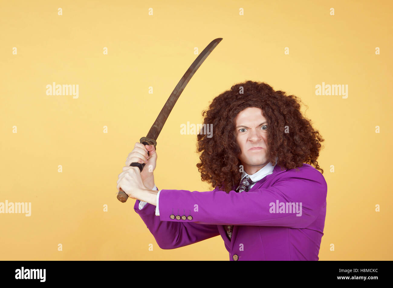 Caucasian man with afro wearing Purple Suit carrying sword Stock Photo