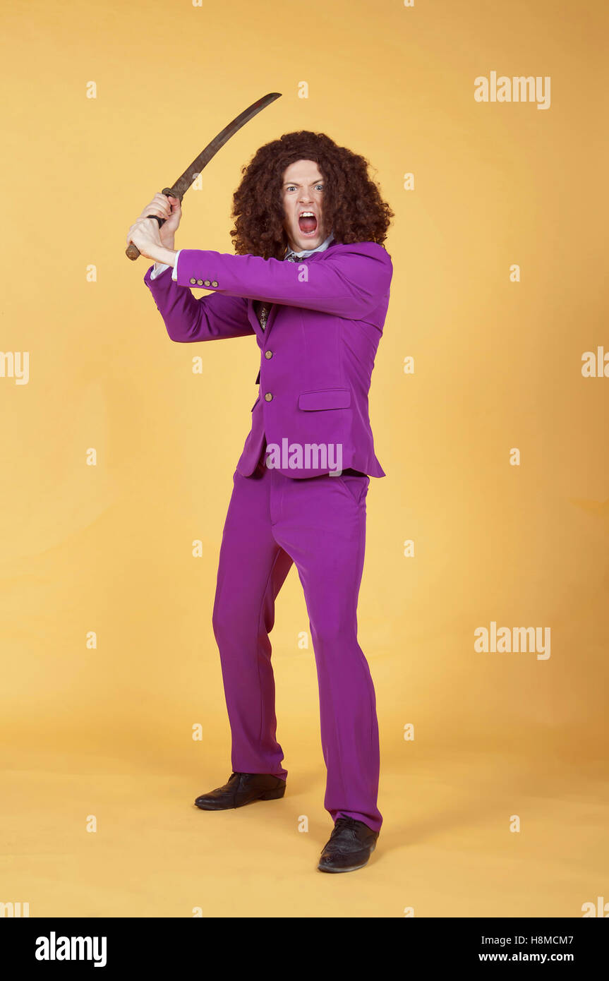 Caucasian man with afro wearing Purple Suit carrying sword Stock Photo