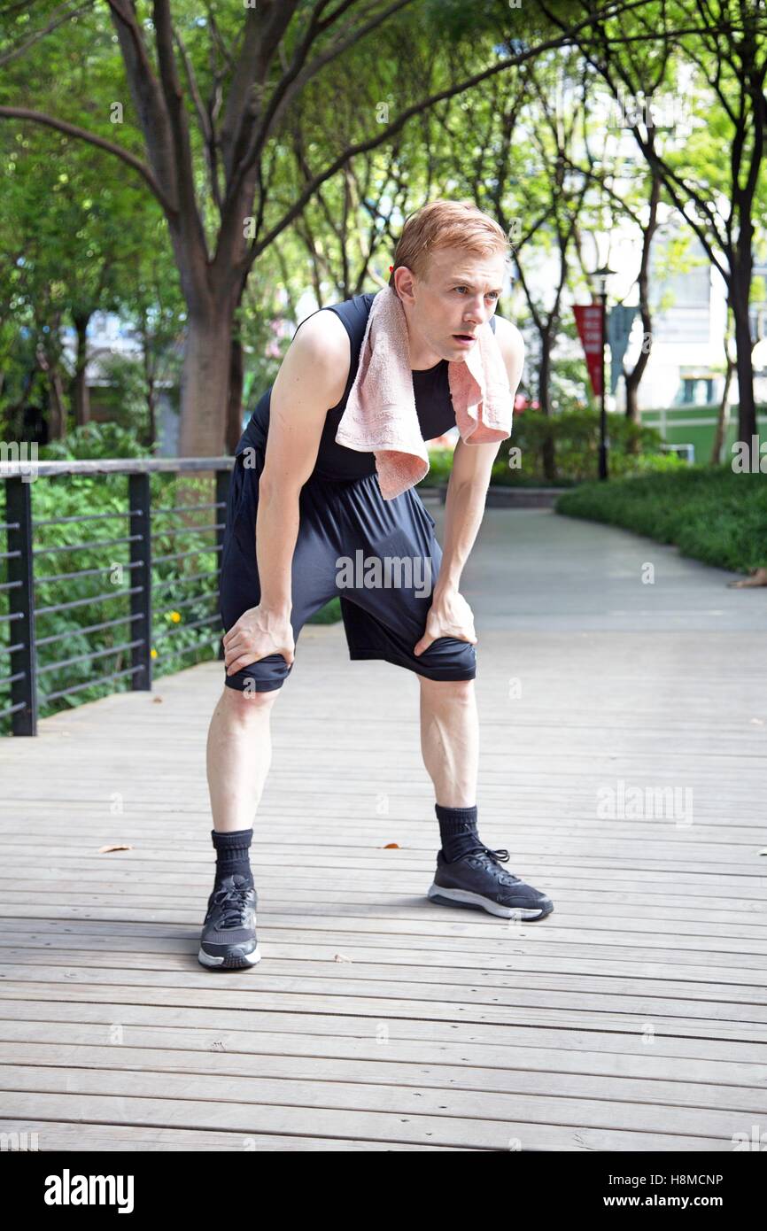 Exhausted caucasian man after a run with towell Stock Photo