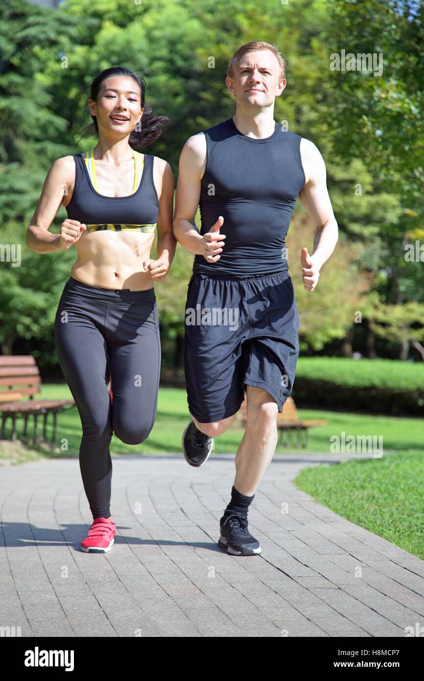 Multi ethnic couple running in park Stock Photo