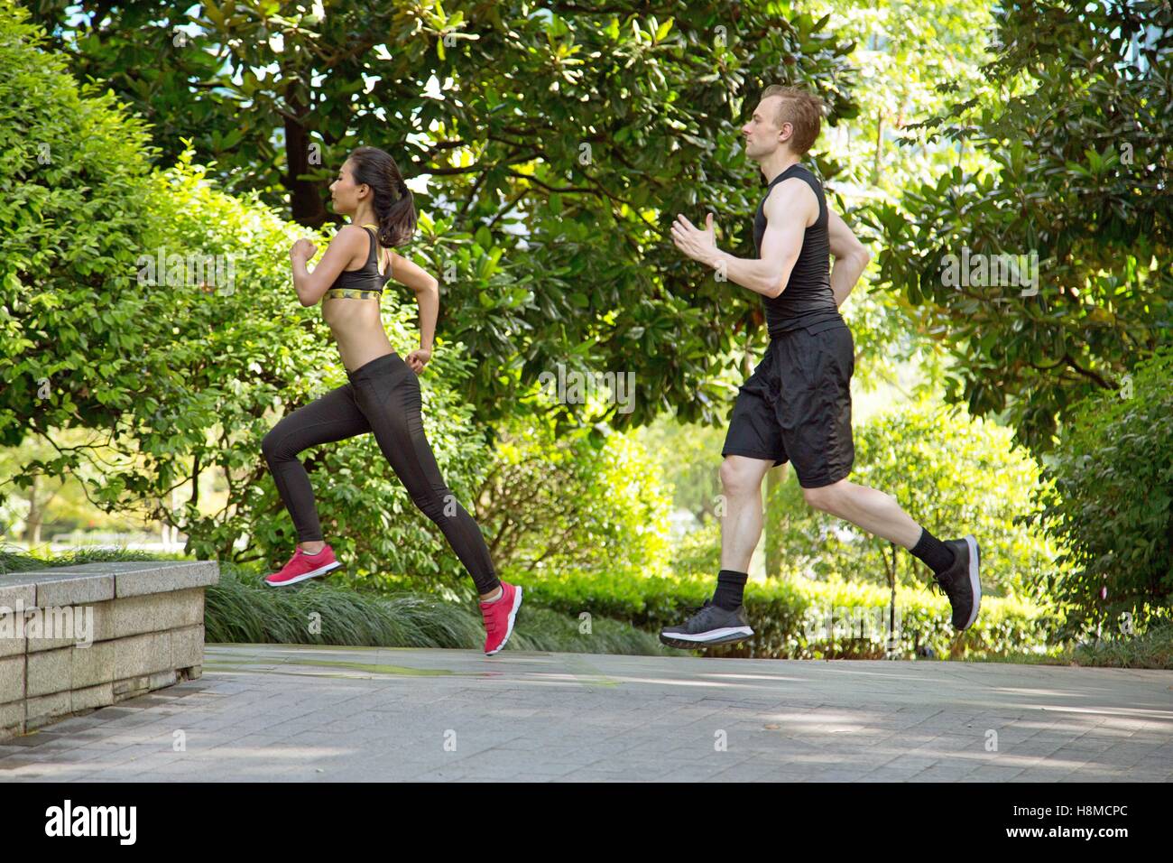 Side view of Multi ethnic couple running in park Stock Photo