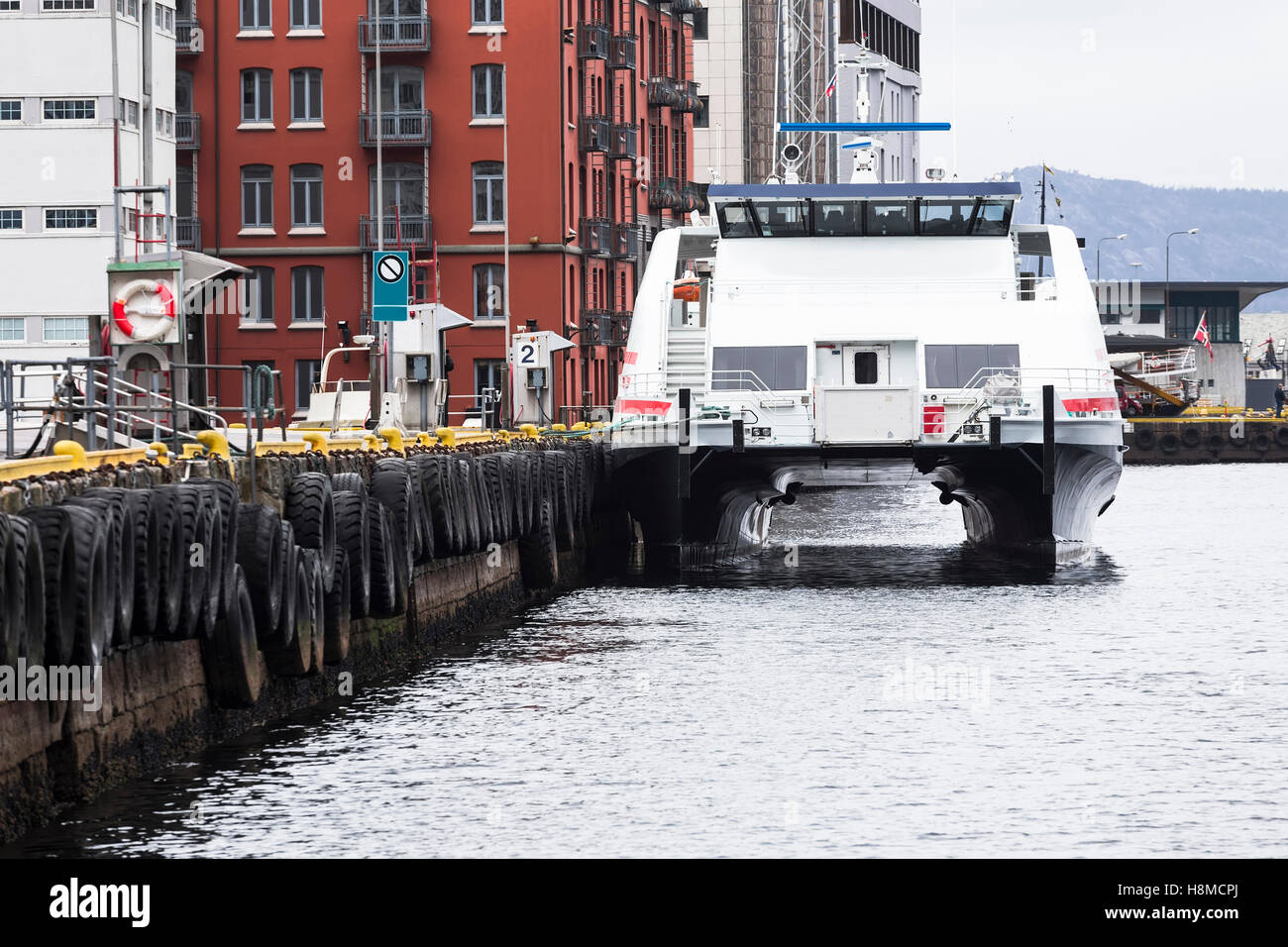 Passenger catamaran at the pier with old tires Stock Photo