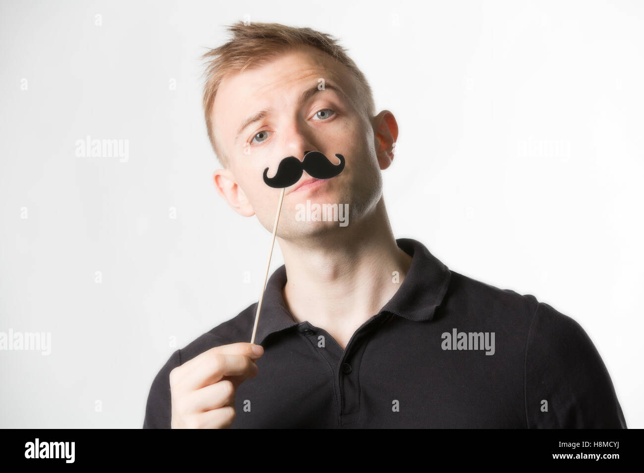 Portrait of an attractive young man wearing a retro style fake mustache. Stock Photo