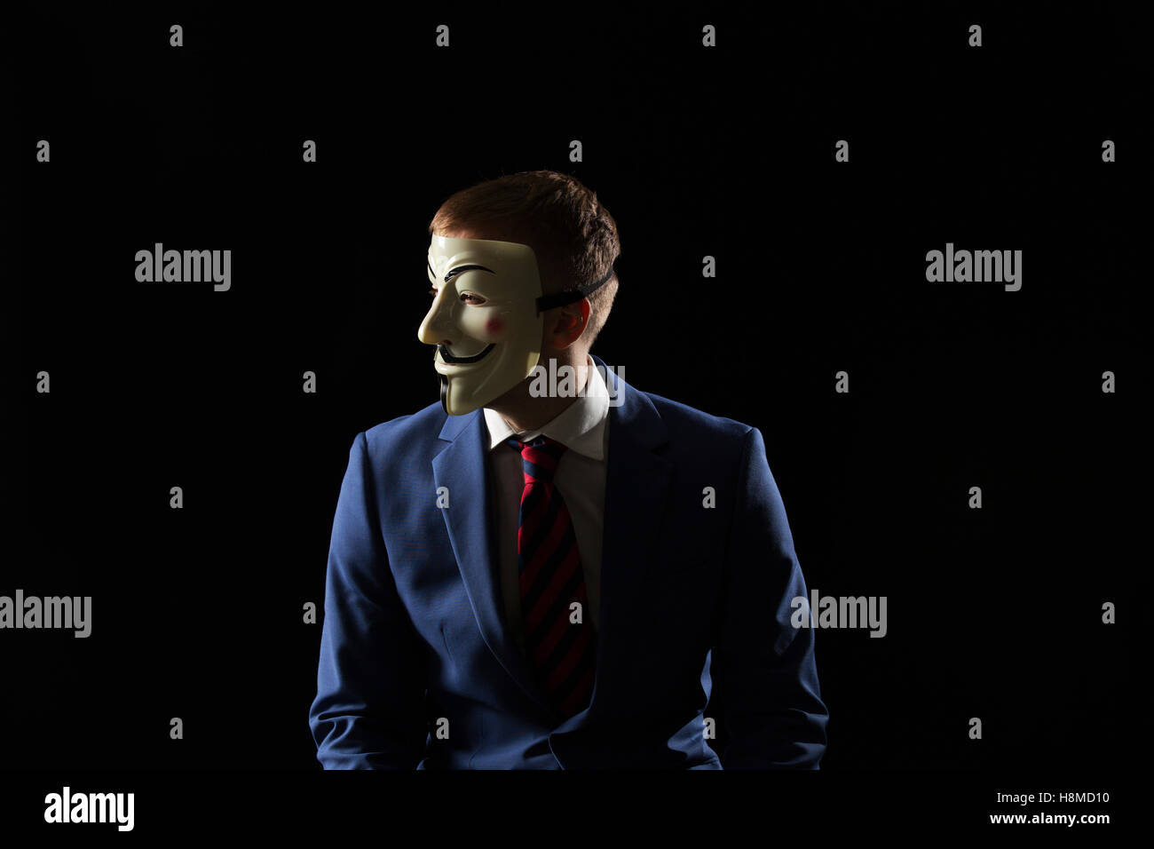 Business man under the mask disguise being  Anonymous and implying that he is a hacker or anarchist Stock Photo