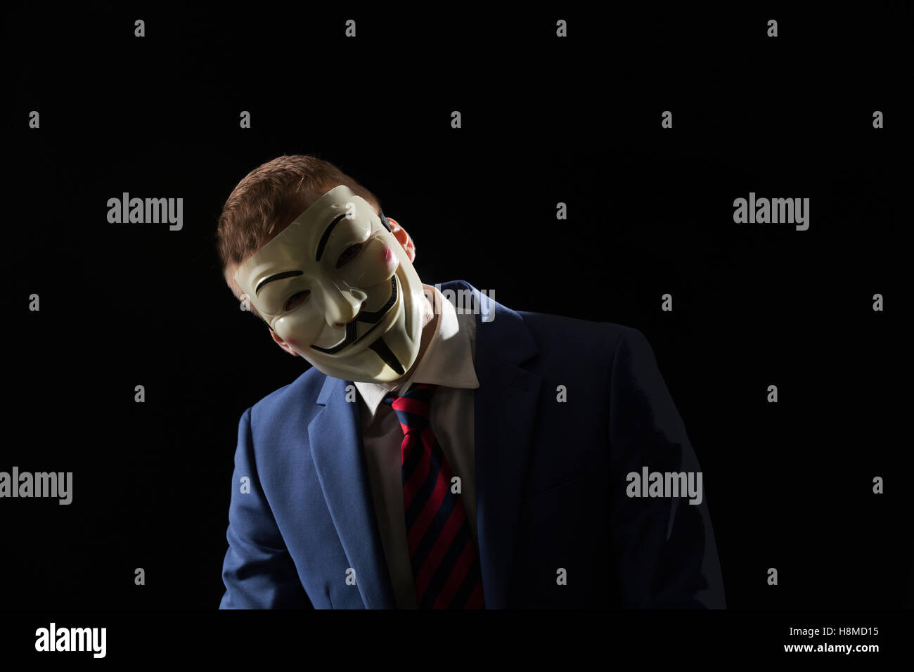 Business man under the mask disguise being  Anonymous and implying that he is a hacker or anarchist Stock Photo