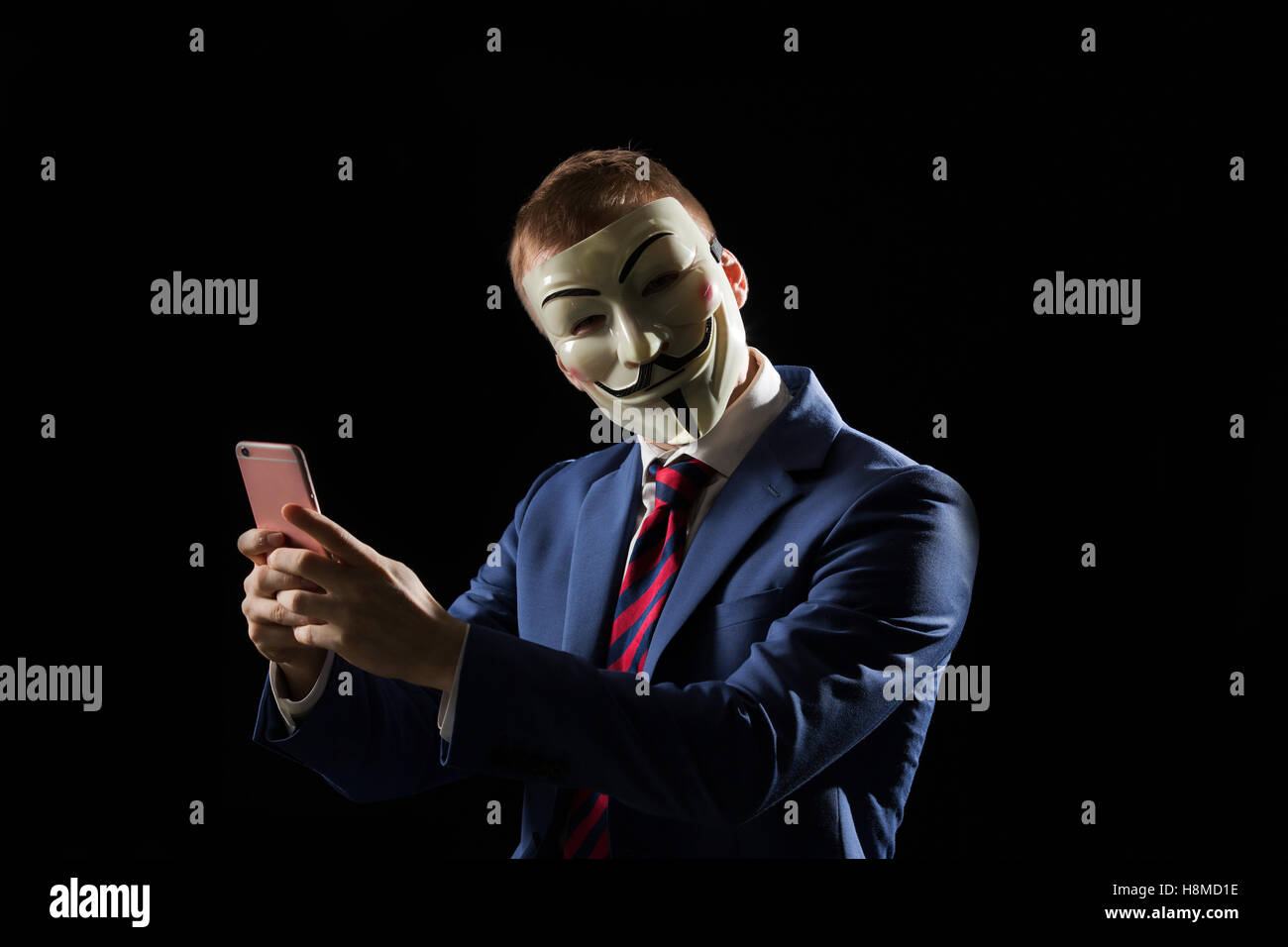 Business man under the mask disguise being  Anonymous and implying that he is a hacker or anarchist Stock Photo