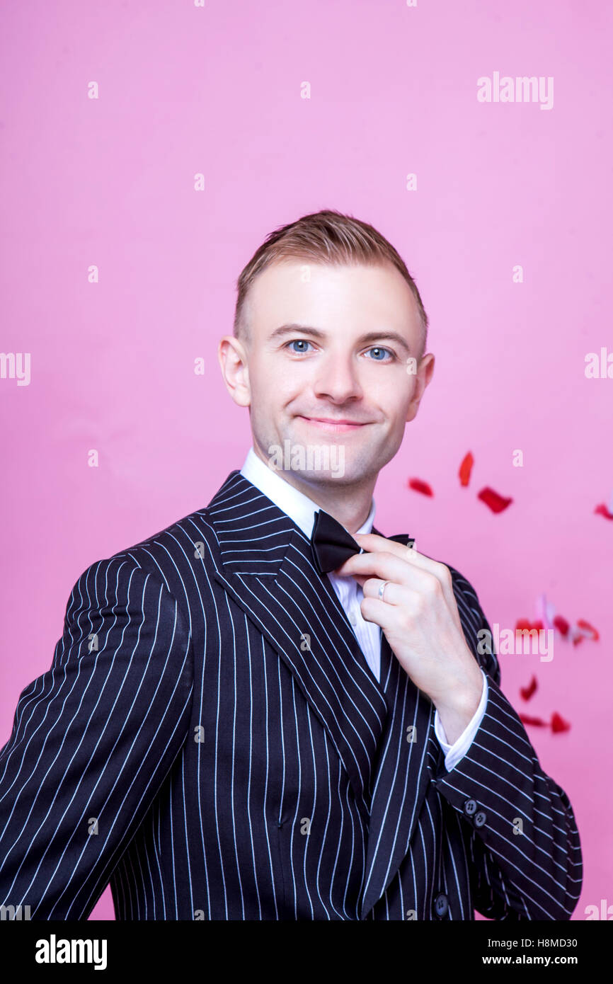 Portrait of smiling bridegroom in striped suit standing against pink background Stock Photo