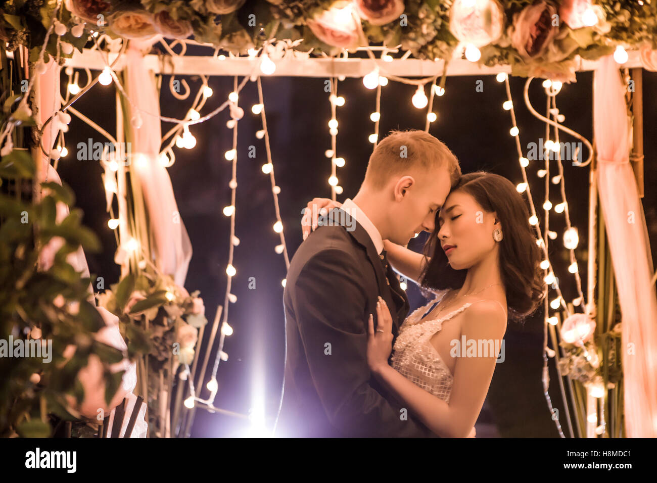Side view of romantic couple embracing in illuminated gazebo at night Stock Photo