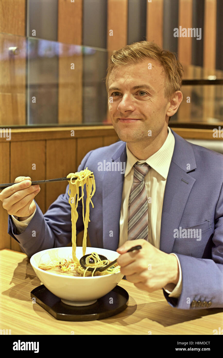 Caucasian man eating noodles in restaurant Stock Photo