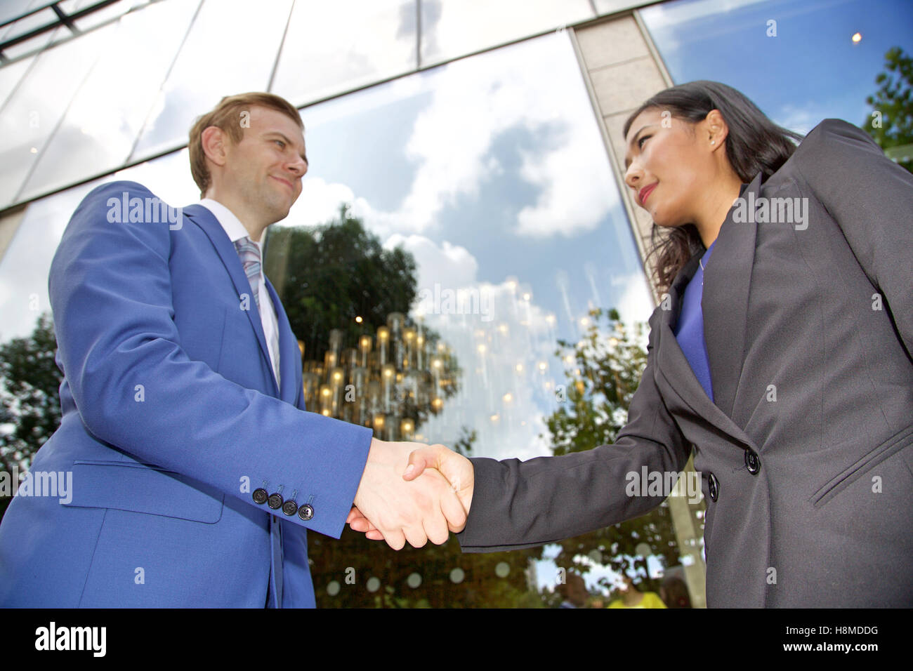 Low angle view of Multi ethnic business couple shaking hands Stock Photo