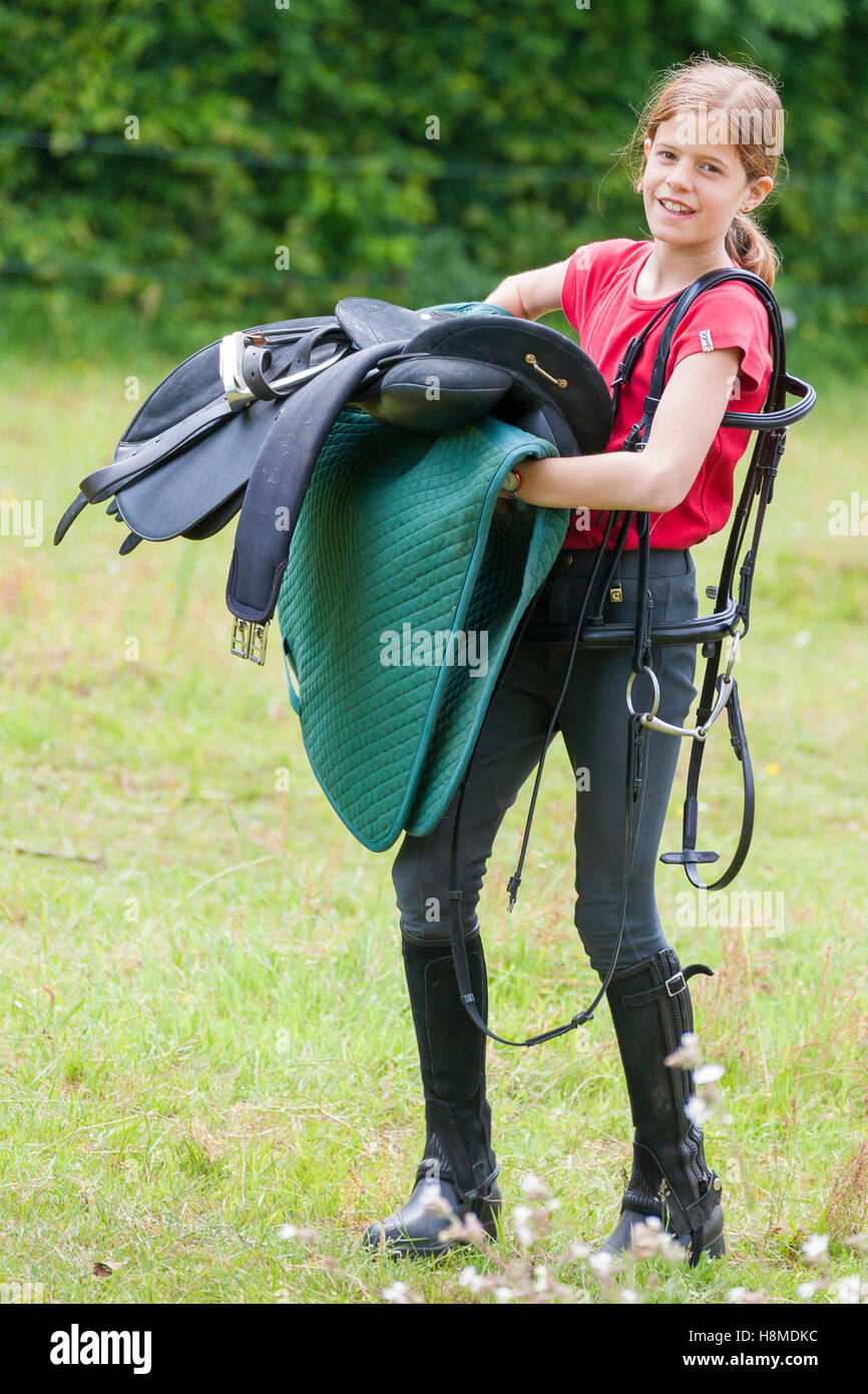 Girl carrying saddle and bridle. Germany Stock Photo - Alamy
