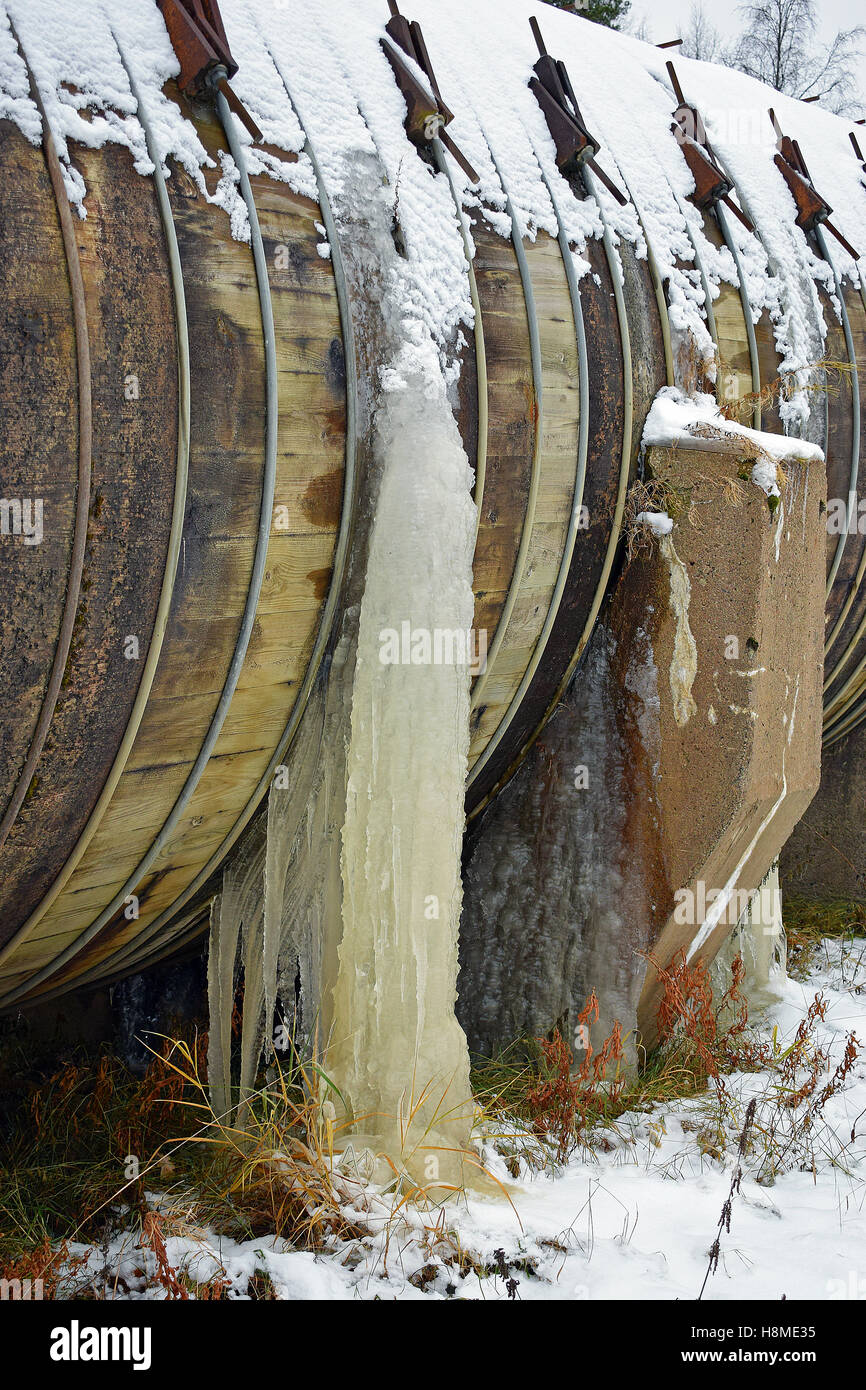 Closeup of old wooden water pipe in wintertime. Ice formed from trough pipe leaks. Stock Photo