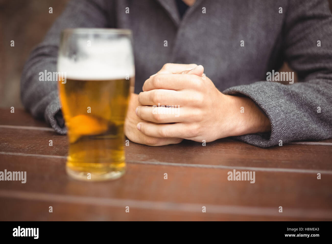 Man sitting in bar with glass of beer on table Stock Photo