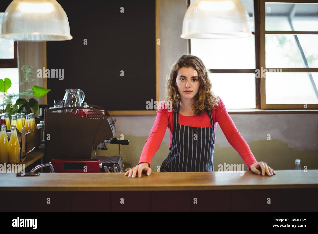 Confident waitress standing at counter in cafÃ© Stock Photo